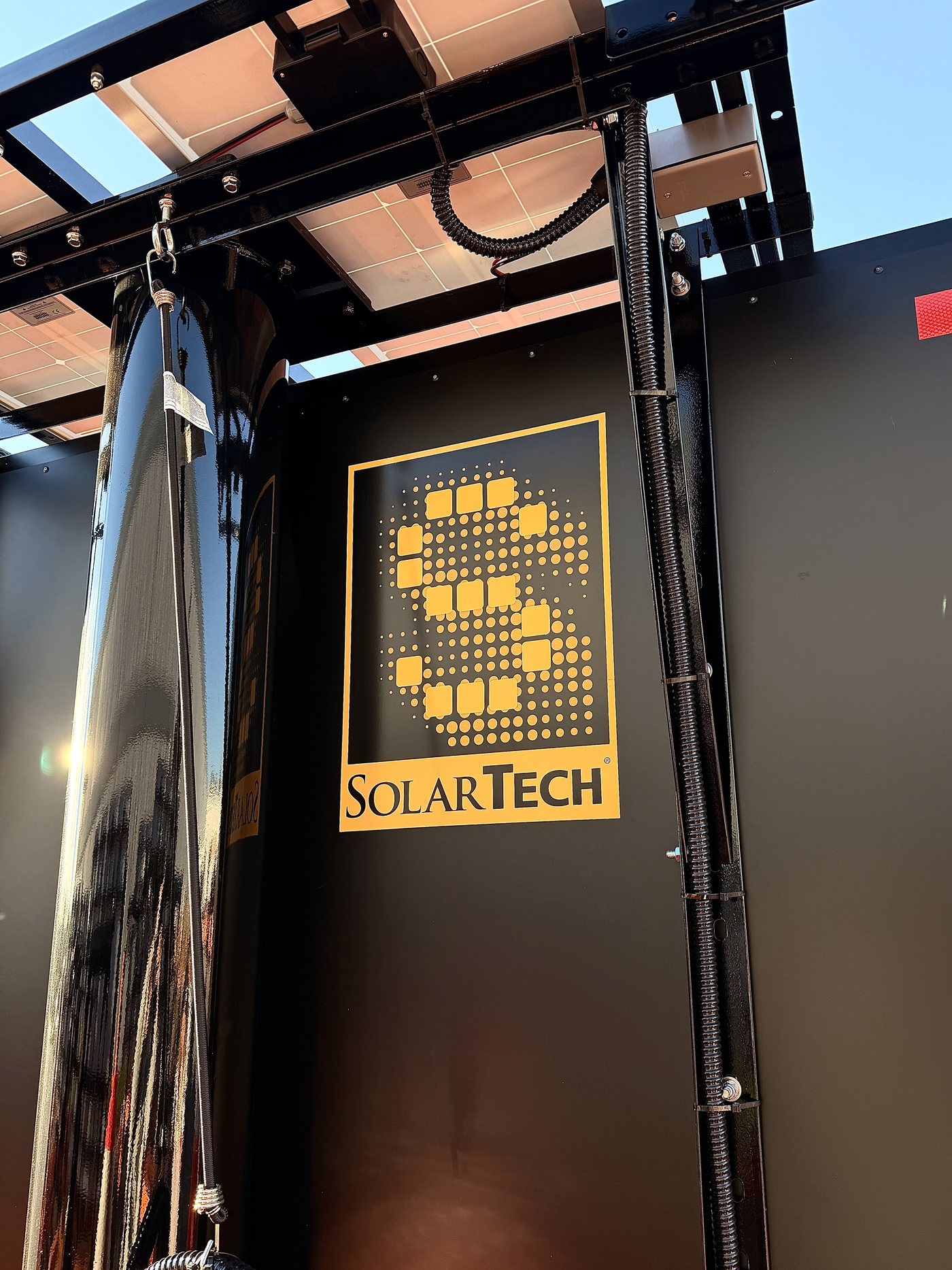 The SolarTech logo on the black powder-coated panel of a trailer, with the solar array above